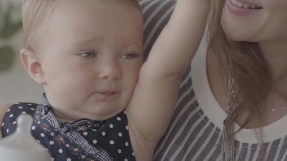 Close-up of a Beautiful Baby Girl Drinking Water From the Small Baby Bottle with Mother's Help in