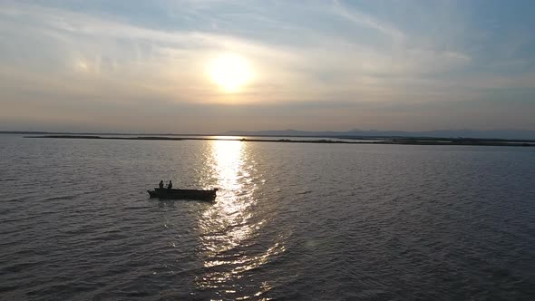 Fisherman in a boat fishing on a river in a sunset.