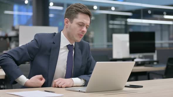 Businessman Having Back Pain While Using Laptop in Office