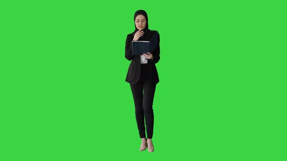 Muslim Businesswoman Reading Her Business Planner While Walking To the Meeting on a Green Screen