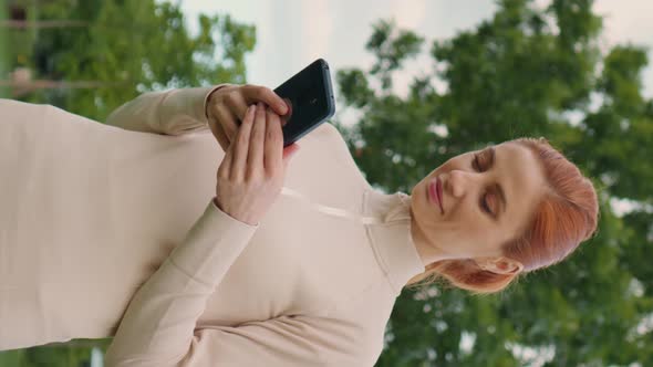 Vertical Screen Woman holding mobile phone while morning workout, gym exercises.