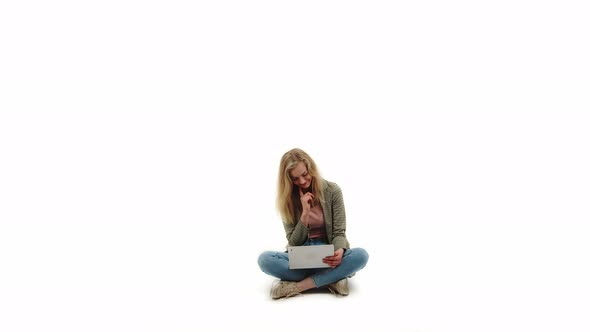 Cute Young Adult Semiformally Dressed Caucasian Blond Caucasian Girl Sitting Crosslegged with Laptop