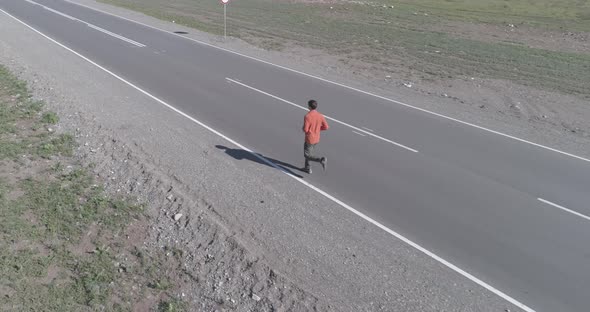 Low Altitude Flight in Front of Sporty Man at Perfect Asphalt Road