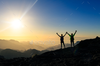 mplish with arms up outstretched. Young man and woman looking at beautiful inspirational landscape view, Gran Canaria Canary Islands.