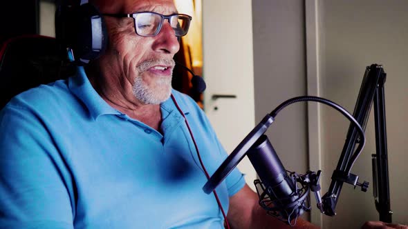 Senior man sitting in studio using computer and microphone