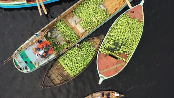 Aerial view of workers exchanging watermelons on boats along the Buriganga River.