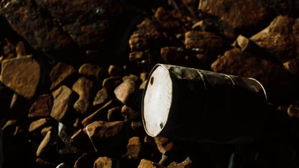 Rusty Destroyed Metal Barrel on Beach Rocks