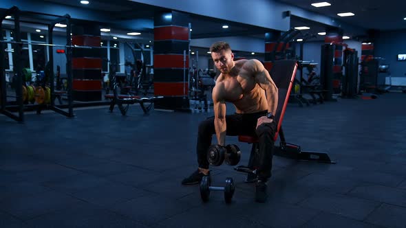 Young muscular man doing hard exercise with dumbbells