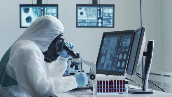 Scientist in protection suit and masks working in research lab using laboratory equipment.