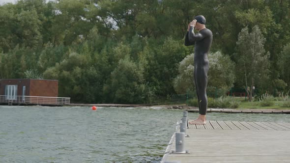 Professional Swimmer in a Wetsuit Jumps Into Open Water Triathlete Trains Before a Triathlon