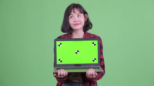 Happy Asian Hipster Woman Thinking While Showing Laptop