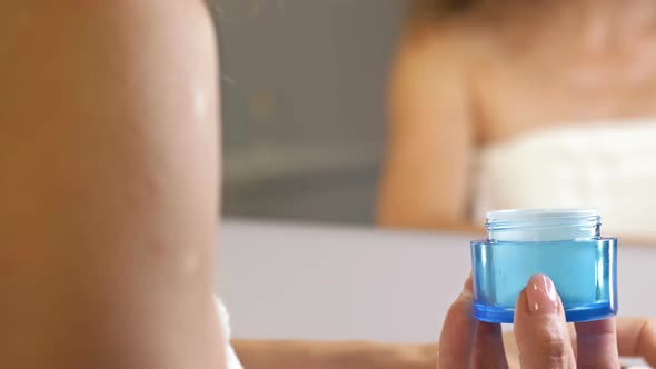 Woman's Hand Holds an Antiaging Moisturizer in a Blue Glass Jar