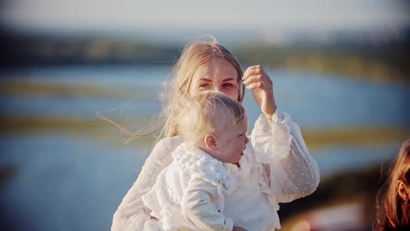 Young Smiling Woman Holding Her Baby While Standing at Nature