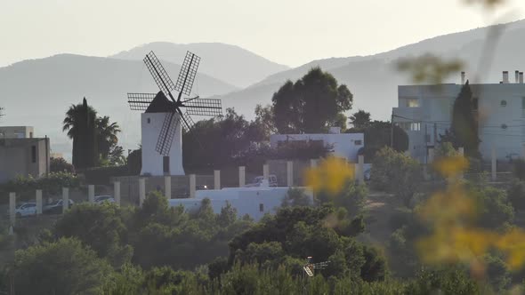 Ibiza, Spain. Windmill and Neighborhood Building on Countryside Hillside, Static Wide View Behind Tr