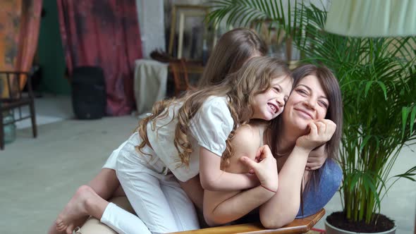 Mom Lies on the Couch and Cuddles with Her Daughters