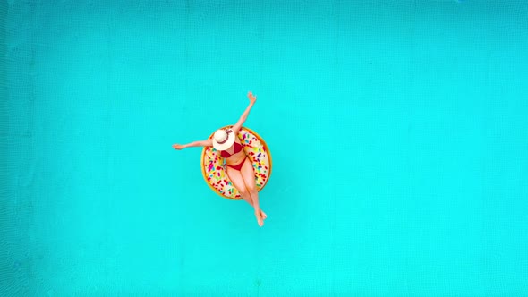 Aerial View of a Woman in Red Bikini Swimming on a Donut in the Pool alt