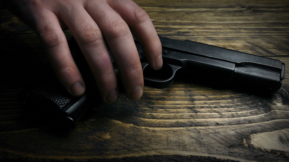 Hand Picks Up Gun Off Table Moving Shot