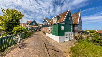 ooden houses and bridge with dike over canal on the island of Marken in the Ijsselmeer or formerly Zuiderzee, the Netherlands