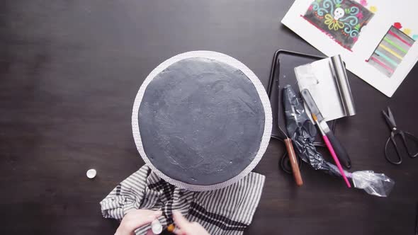 Step by step. Flat lay. Baker applying glittery dust with brush to a black multilayer cake.