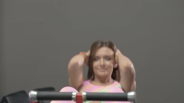 Young woman doing crunches on the bench abs exercising in the gym