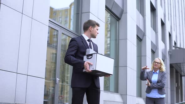 Sad Male Manager With Stuff Box Looking Gloating Female Boss, Company Dismissal