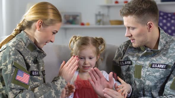 Young Mother and Father in Military Uniform Playing Pat-A-Cake With Daughter