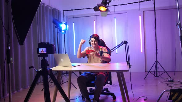 Man Playing Video Game With Mobile Phone Then Celebrating While Live Stream With Light Equipment