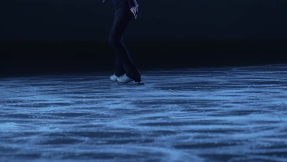 Figure Skating Lady is Skating on Ice Rink Training Alone at Night in the Rays of Blue Light