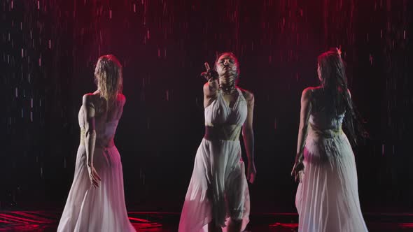 Three Womans in Long White Dresses Are Dancing with Roses in the Rain on a Smoky Background. Slow