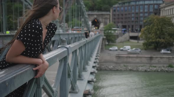 Young Woman on Chain Bridge in European City in Summer Day