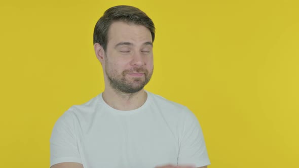 Young Man Pointing on Side on Yellow Background