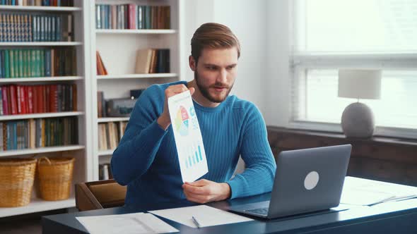 Smiling young businessman sitting at the desk talking on webcam