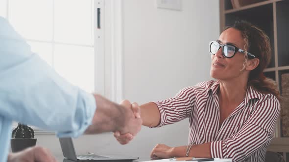 Smiling caucasian female hr manager handshake hire male candidate at job interview