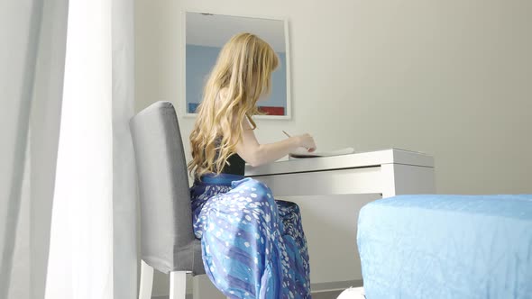 woman taking notes on a piece of paper - a student studying in her room