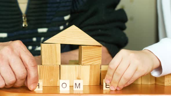 The inscription home from wooden cubes is made up of a child and the hand of an elderly person. Deve