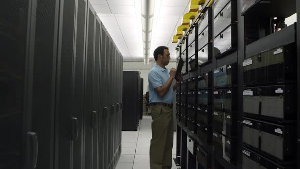 Dolly shot of man looking at network server