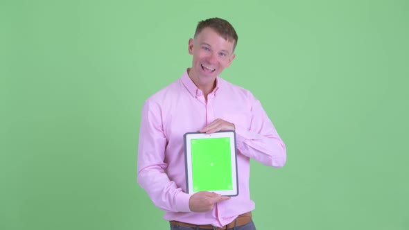 Happy Businessman Showing Digital Tablet and Looking Surprised