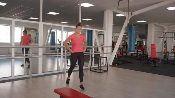 Young Girl Straightens Her Hair in Front of a Mirror in the Gym and Goes to the Bench Do Dumbbell