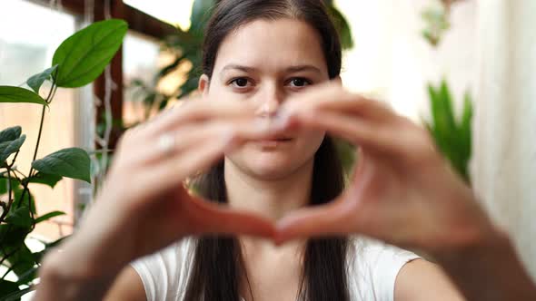 Young RussianUkrainian Girl with the Flag of Ukraine and Russia on Her Face is Showing Heart By