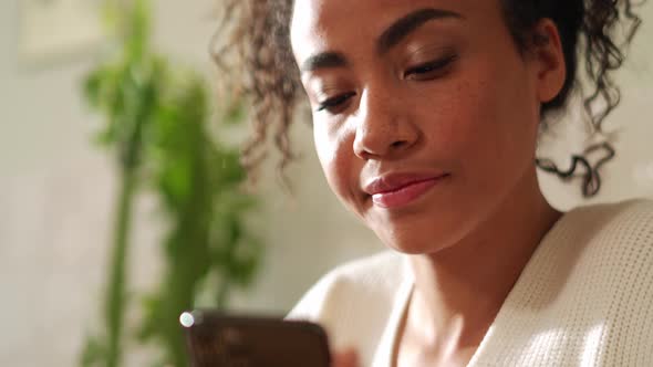 Confident woman looking at phone and drinking coffee