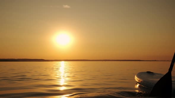 Close Up View of Woman Standing Firmly on Inflatable SUP Board and Paddling Through Shining Water