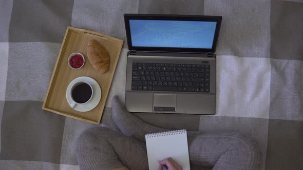 Girl Draws a Graph in Notepad Sitting on the Bed