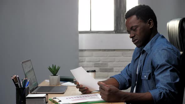 Thoughtful African American Businessman Looks Business Report in Office