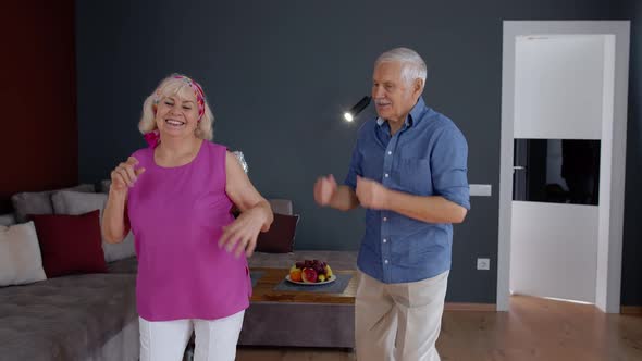 Senior Couple Dancing Laughing at Home. Grandparents Relaxing Having Fun Celebrating Anniversary