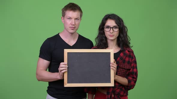 Young Couple Holding Blackboard Together