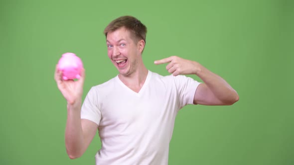 Young Handsome Man Holding Piggy Bank and Giving Thumbs Up