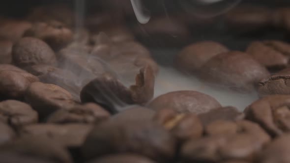 Close up macro shot of a cracked coffee bean, smoke coming from the roasting beans which accelerates