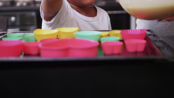 Black Little Girl Pouring Dough in the Little Forms