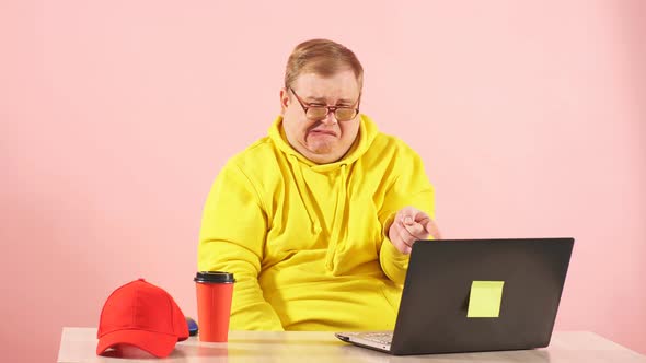 Crying Man in Yellow Hoodie Watching Sad Movie on Laptot and Pointing at Screen