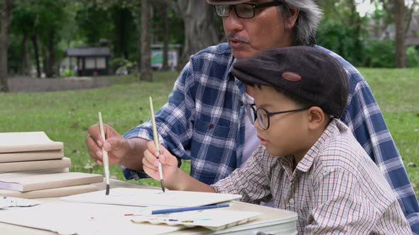 Senior man and boy drawing with water color